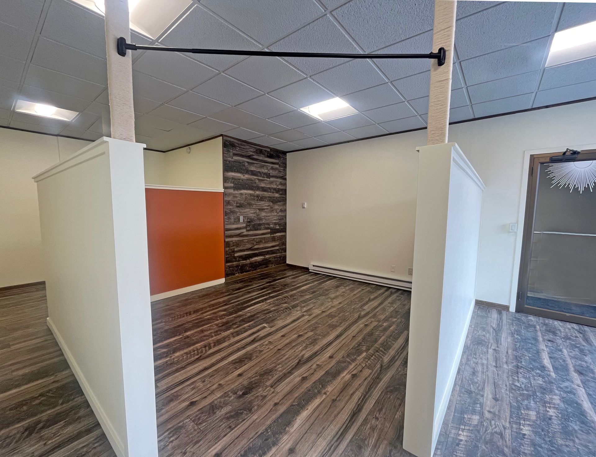 Empty room with wood-look floors, white walls, and an accent wall of dark wood planks.