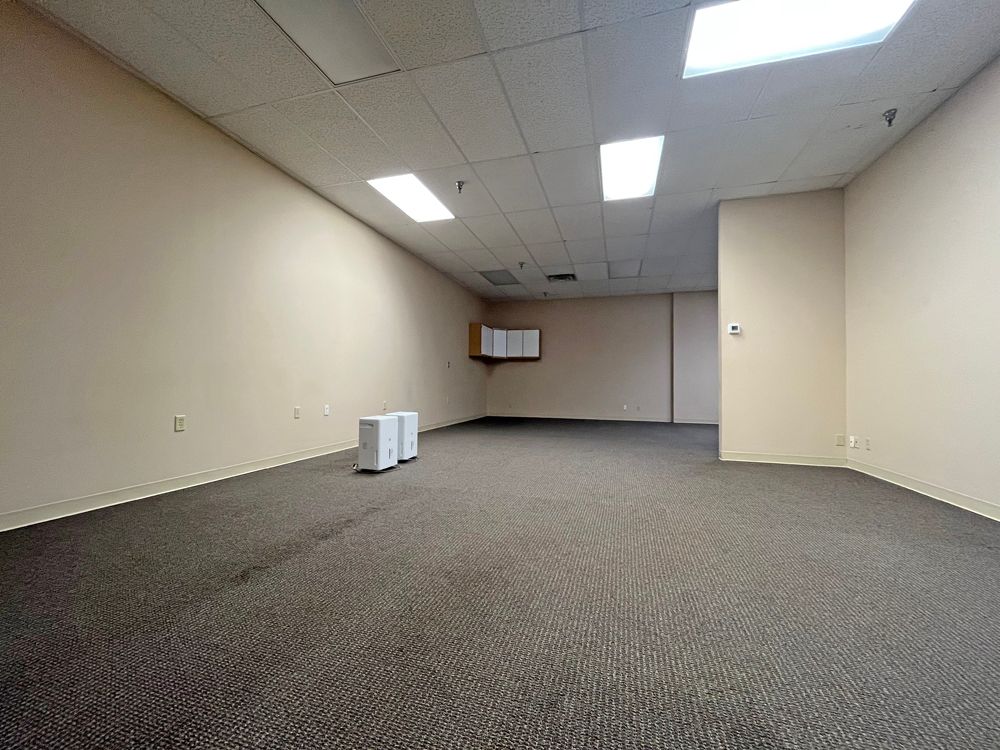 An empty room with a carpeted floor and white walls