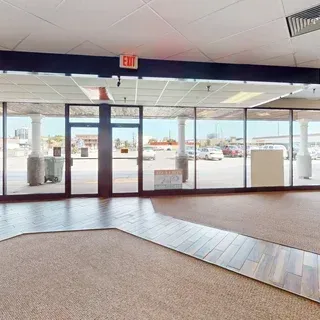 Empty commercial interior with large windows facing a parking lot, 