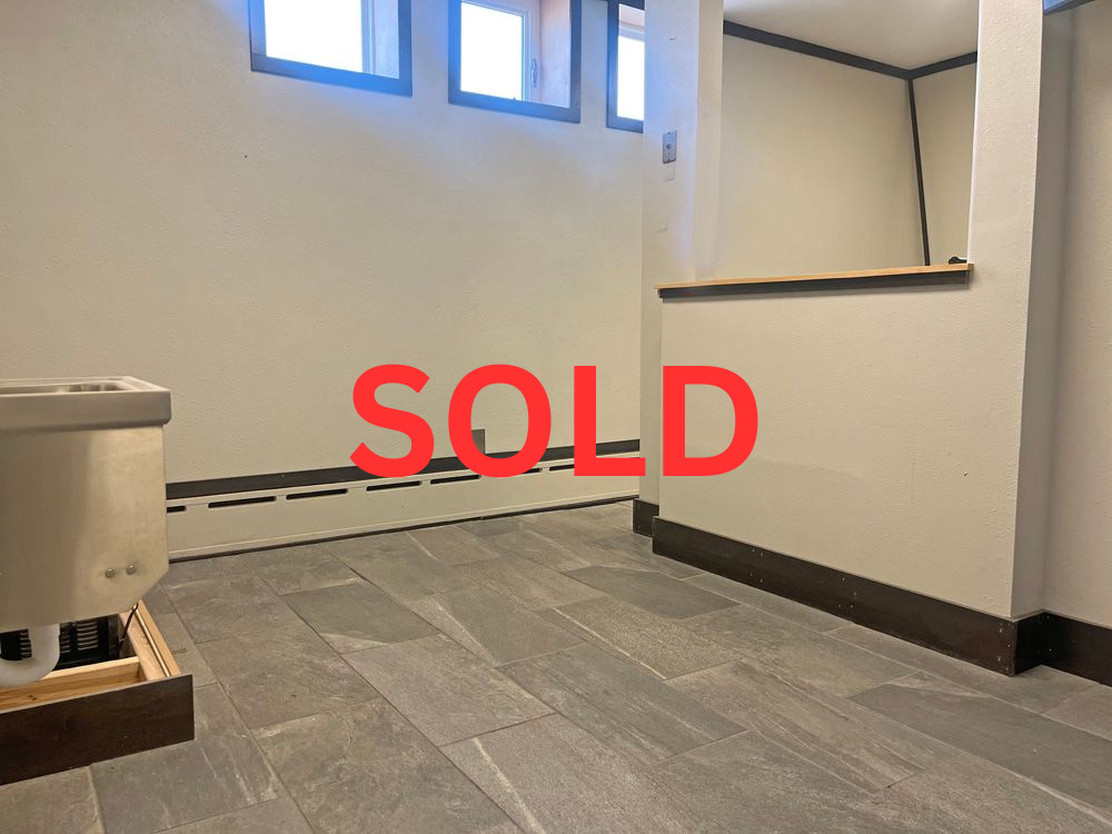 Empty room with tiled floor, low windows, and the word