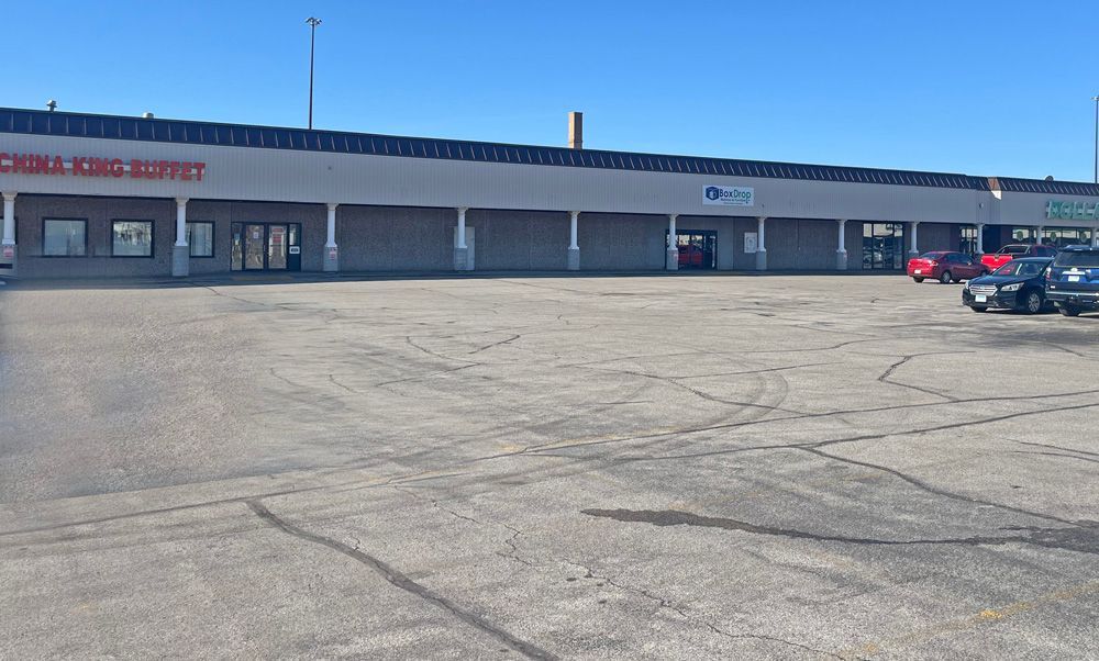 A strip mall with a vacant parking lot, featuring China King Buffet. Sunny day.