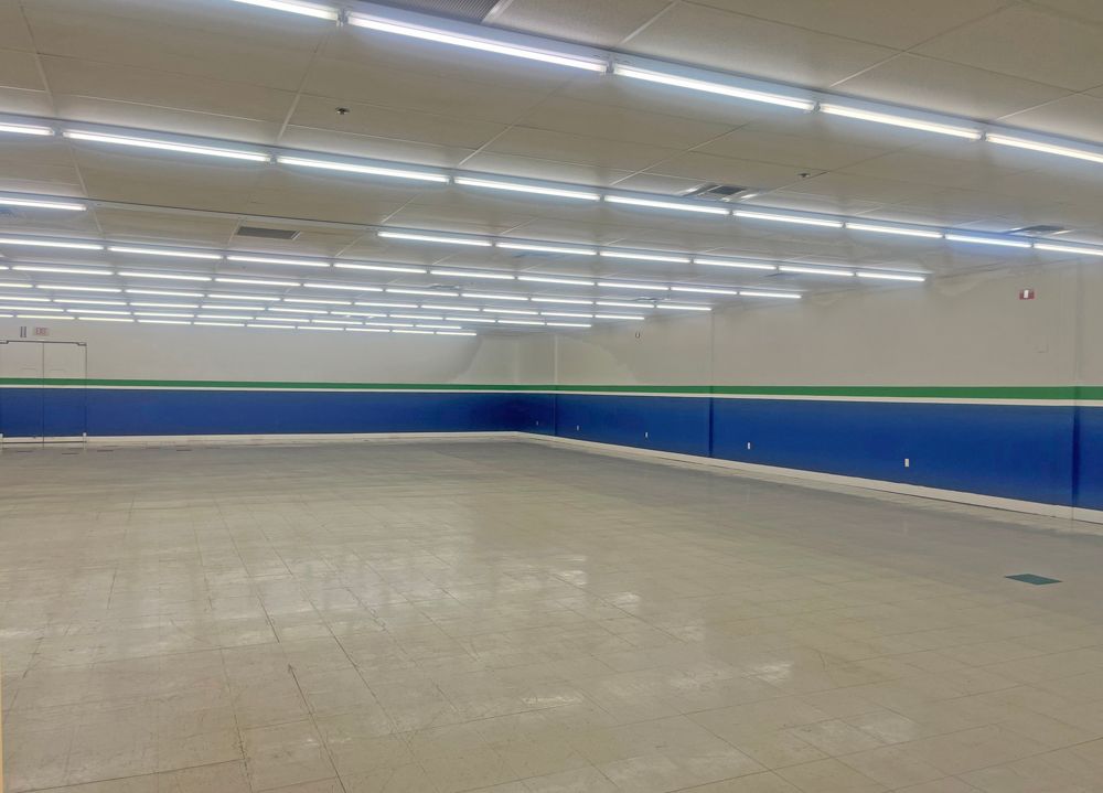 Empty, spacious retail interior; blue and green wall accents, bright overhead lights.