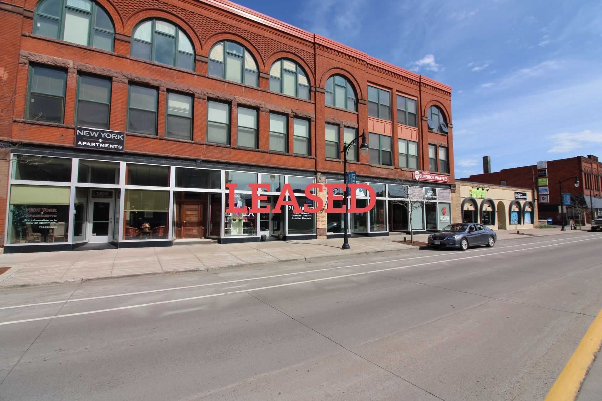 a car is parked in front of a large brick building