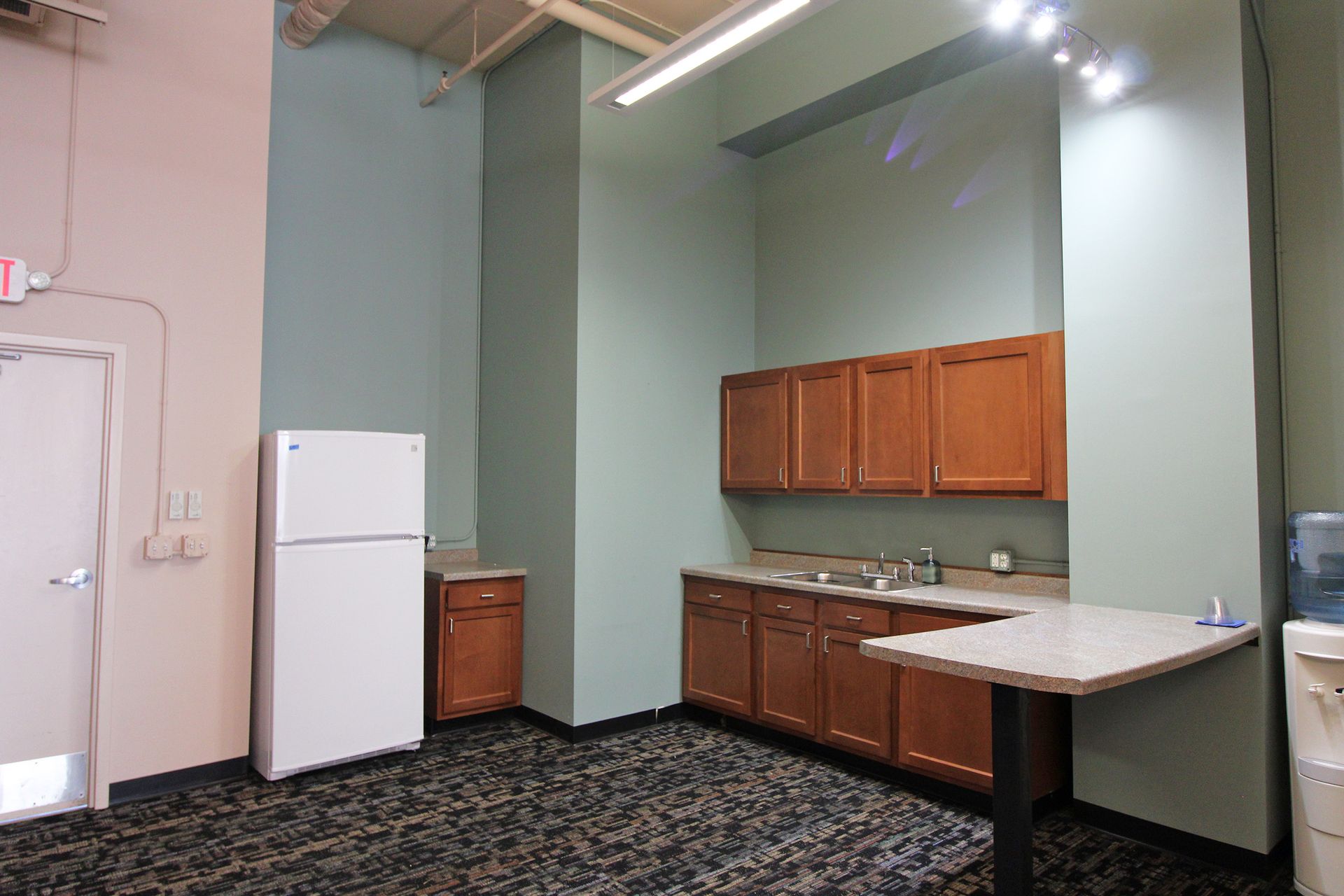 a kitchen with a refrigerator, sink, cabinets and a table