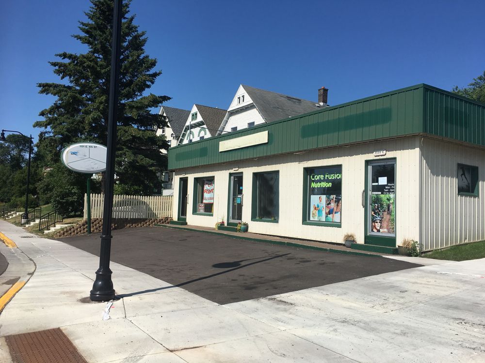 a white building with a green roof is sitting on the side of the road
