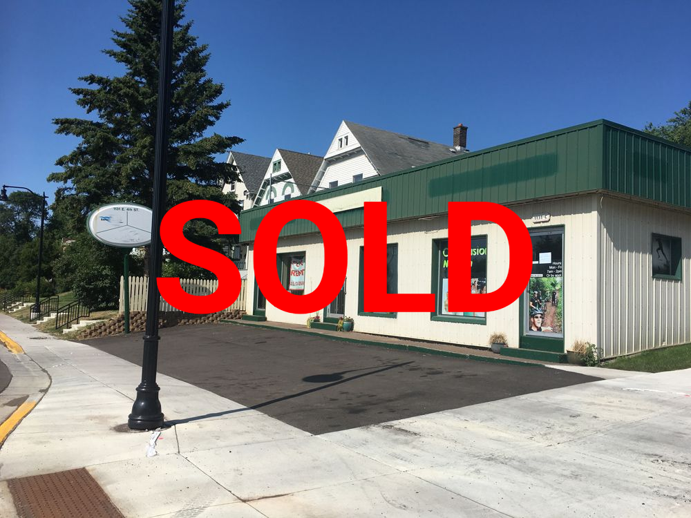 a white building with a green roof is sitting on the side of the road