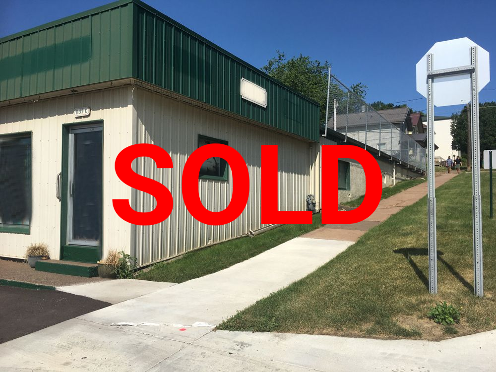 a building with a green roof is next to a sidewalk