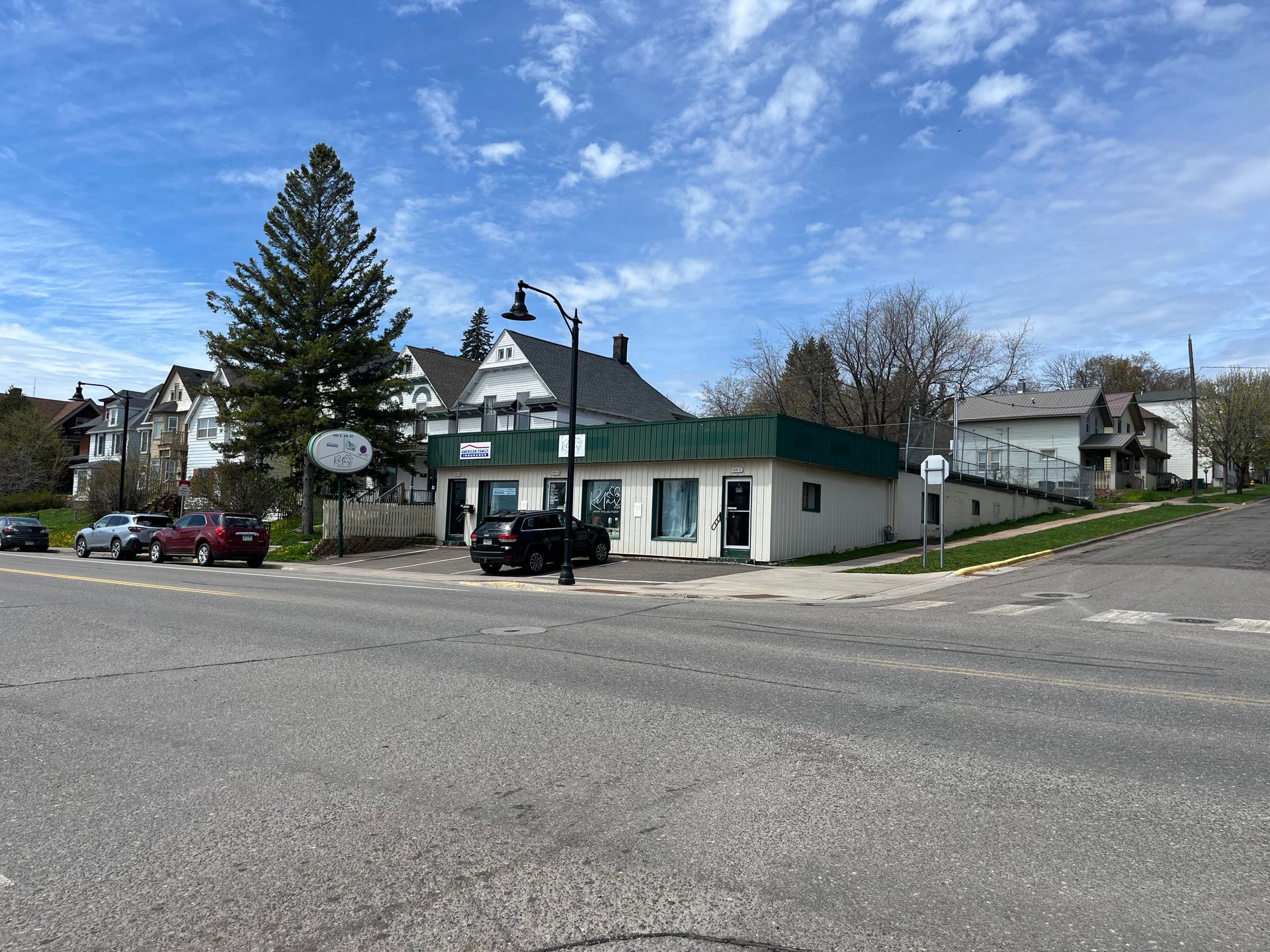 a white building with a green roof is sitting on the corner of a street