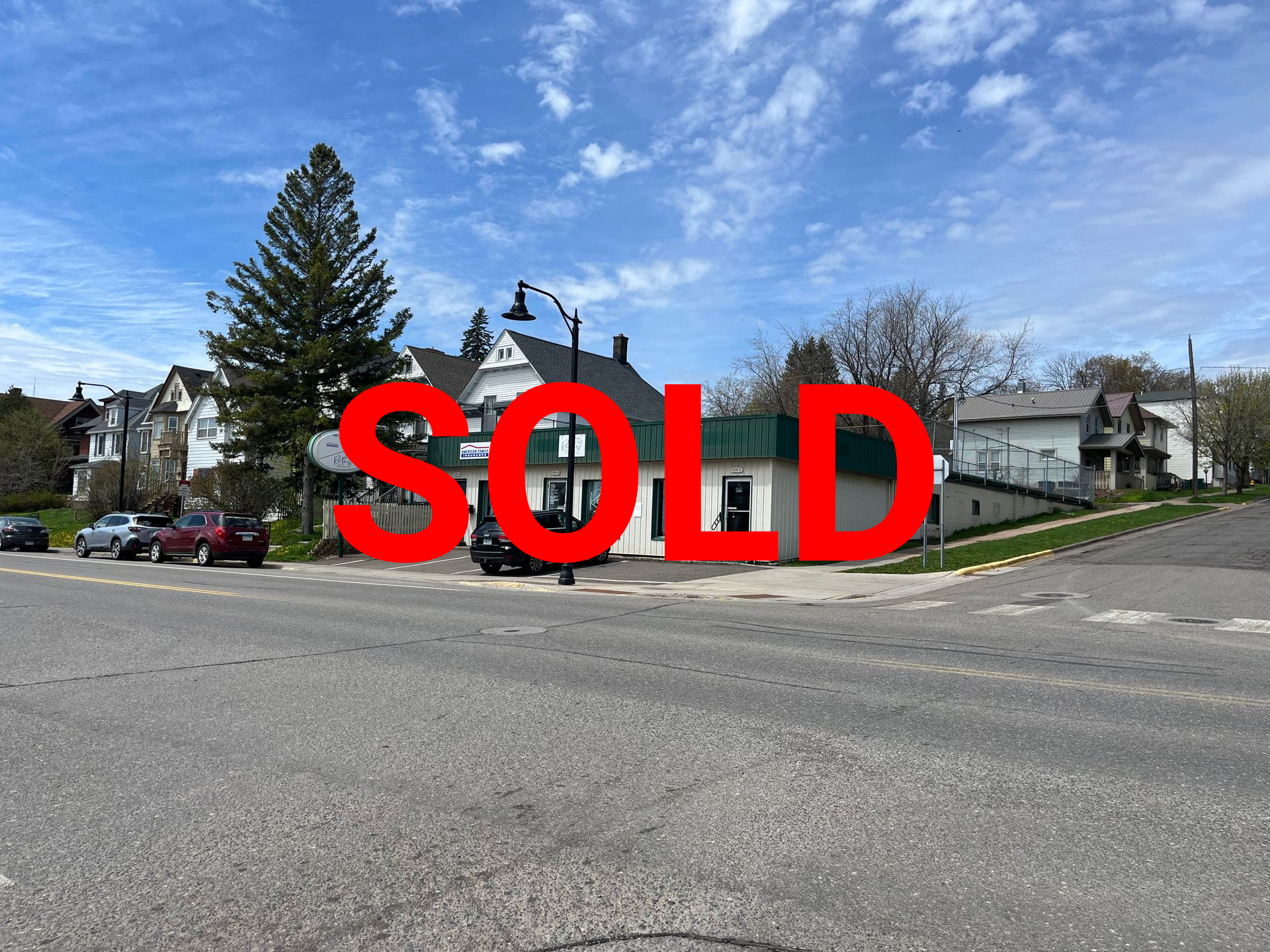 a white building with a green roof is sitting on the corner of a street