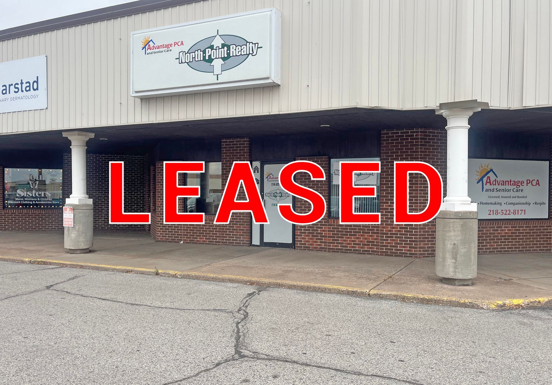 Storefront with large red “LEASED” sign across the front windows