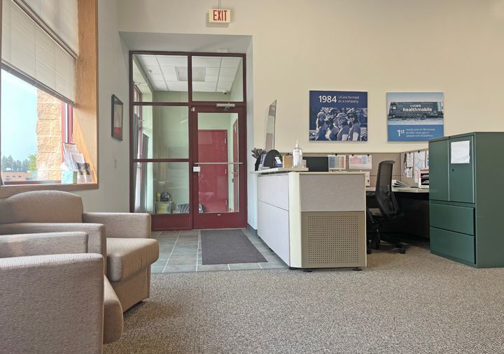 A waiting room with chairs , a desk and an exit sign