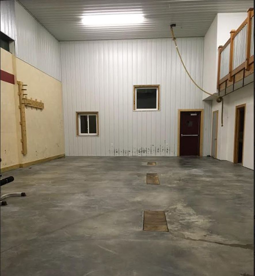 A large empty room with concrete floors and white walls
