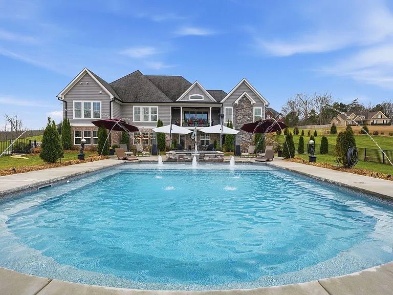 Swimming pool with decorative compass design on the stone patio. Surrounding fence and foliage.