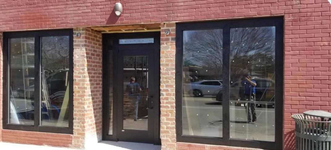 a brick building with a lot of windows and a trash can in front of it