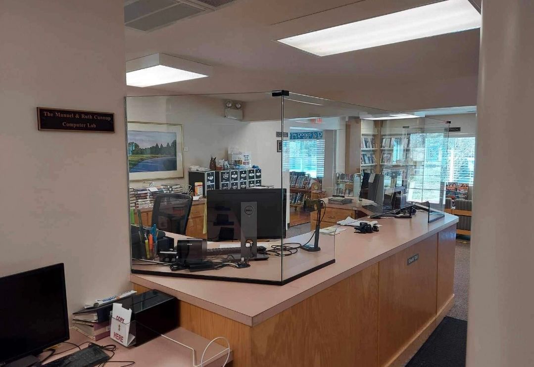 a computer is sitting on a desk in front of a glass barrier