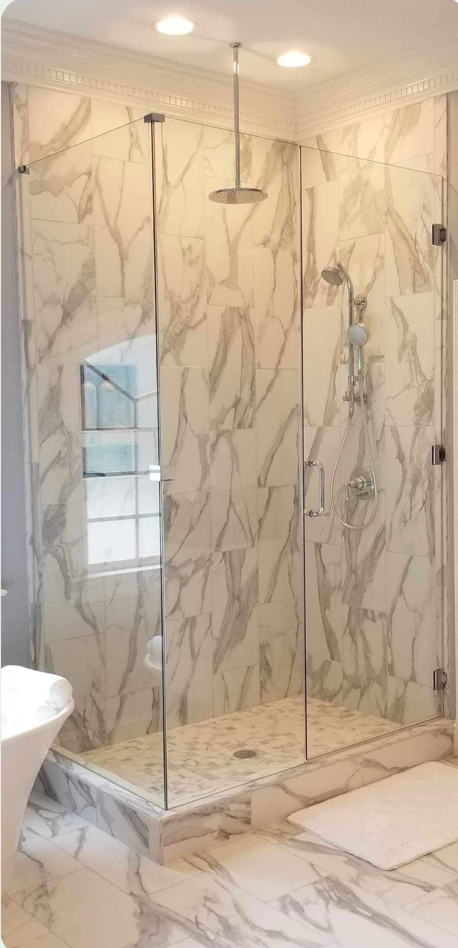 a bathroom with a walk in shower and marble walls