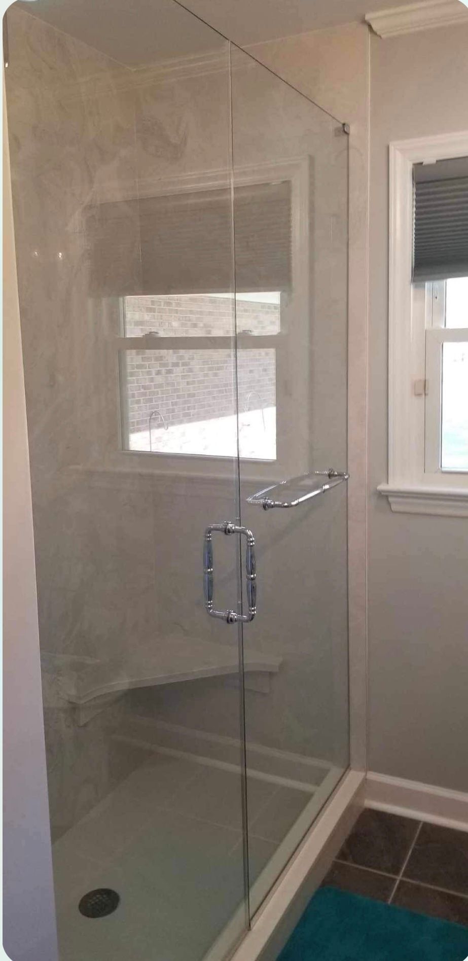 a bathroom with a glass shower door and a window