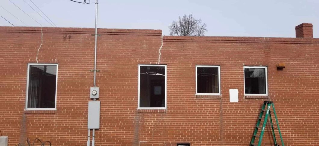 a brick building with a lot of windows and a ladder in front of it