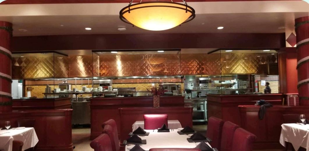 a restaurant with tables and chairs and a kitchen in the background