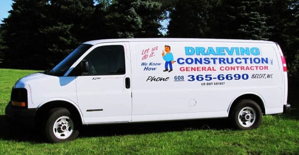 White construction van with company logo parked on grass.