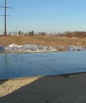 A sheet of ice covers a road in a rural landscape on a sunny day.
