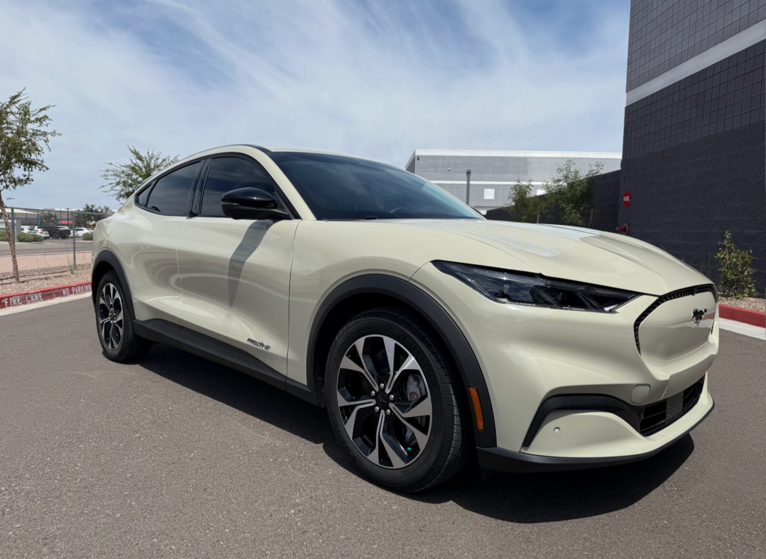Cream-colored electric SUV parked on a street beside a building under a clear sky