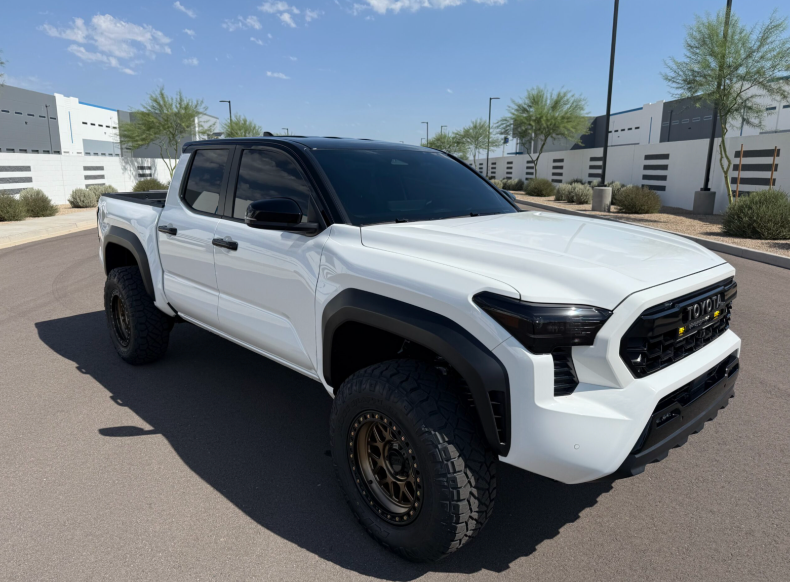 White off-road pickup truck parked on a sunny street with black trim and tinted windows