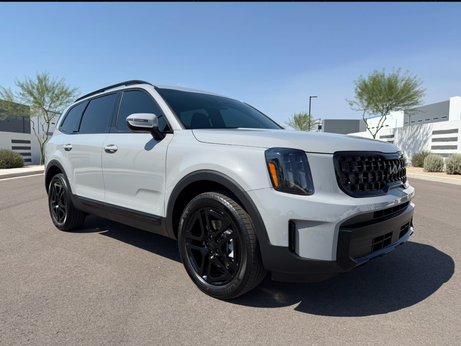 White SUV parked outdoors on a sunny street, front-left view, with black wheels and tinted windows