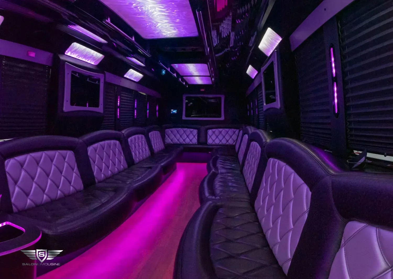 Interior of a purple-lit party bus with black and silver diamond-patterned seating.