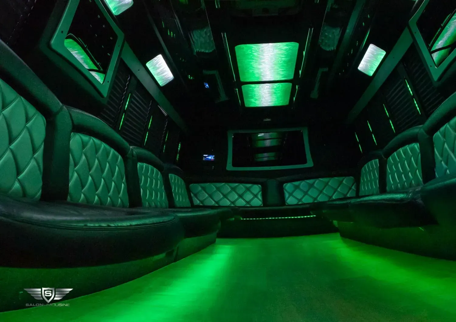 Interior of a limousine with green neon lights and black and green leather seating.
