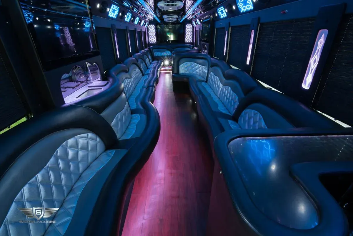 Interior of a limousine with blue and purple lighting, diamond-stitched seating, and a long aisle.