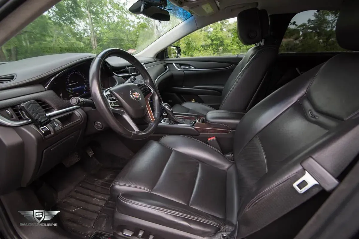 Black leather interior of a Cadillac, with steering wheel, dashboard, and front seats.