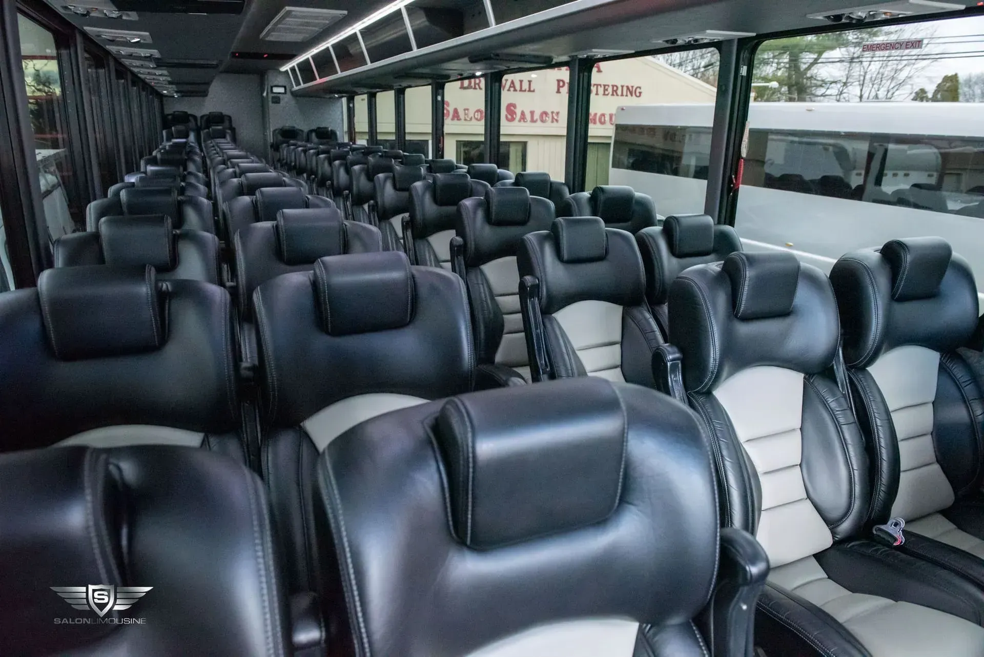 Interior of a black and gray passenger bus with rows of seats. Sunlight streams in from windows.