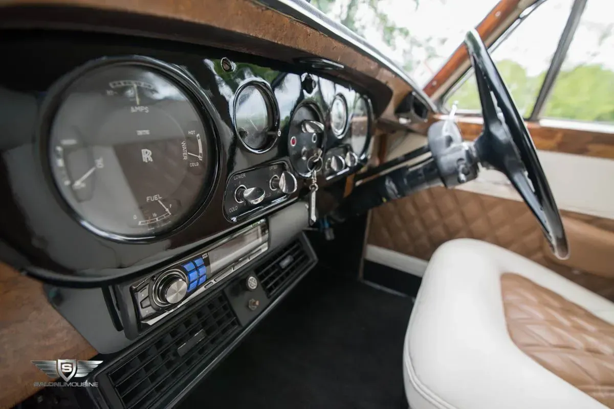 Classic car interior with dashboard, steering wheel, and quilted seats.