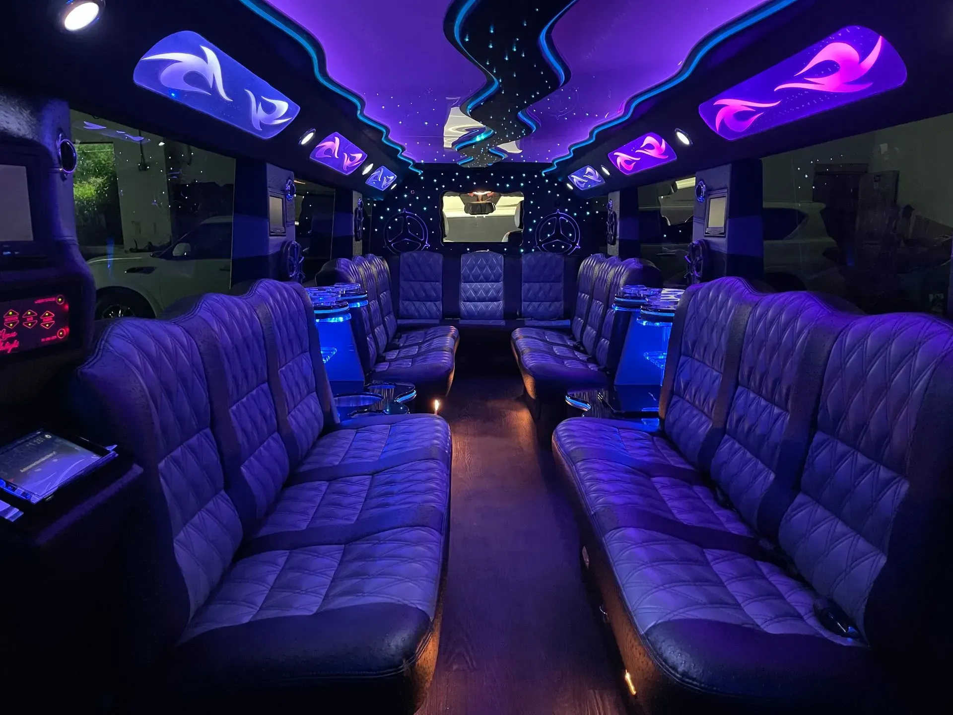 Inside of a party bus with purple and blue LED lighting, leather seating.