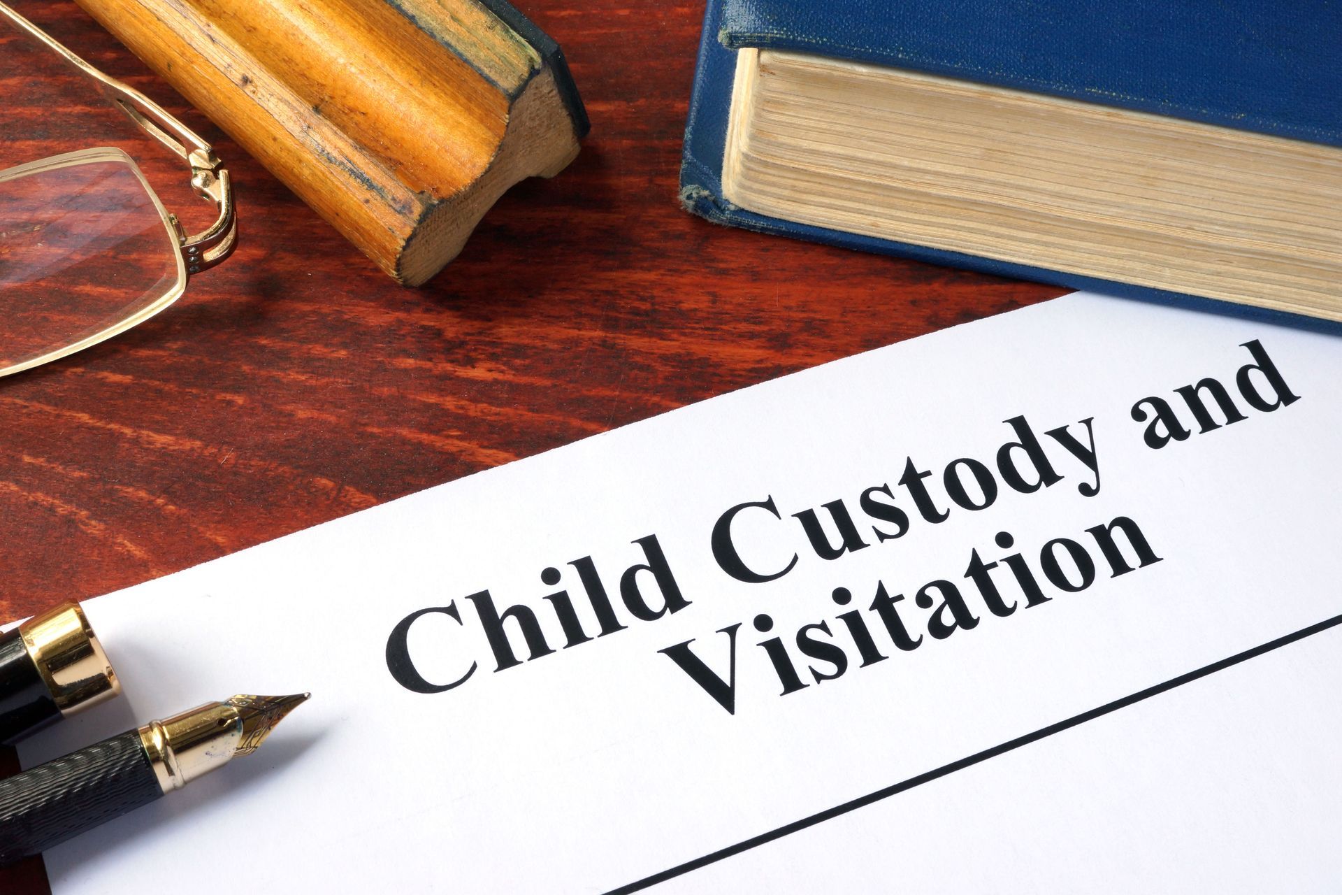 Child custody and visitation document on a desk with glasses and books