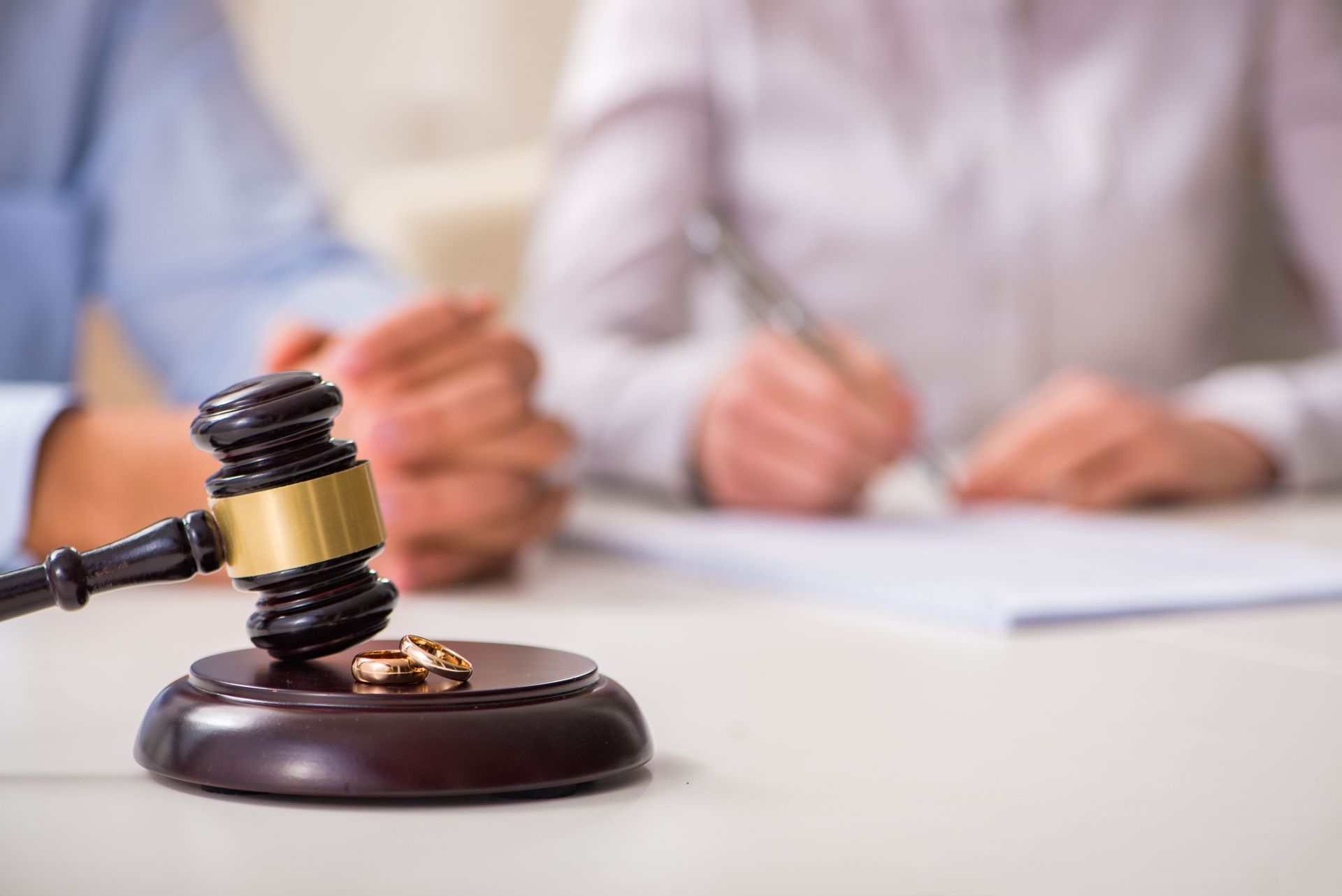 Judge’s gavel on a desk with blurred people signing documents in the background