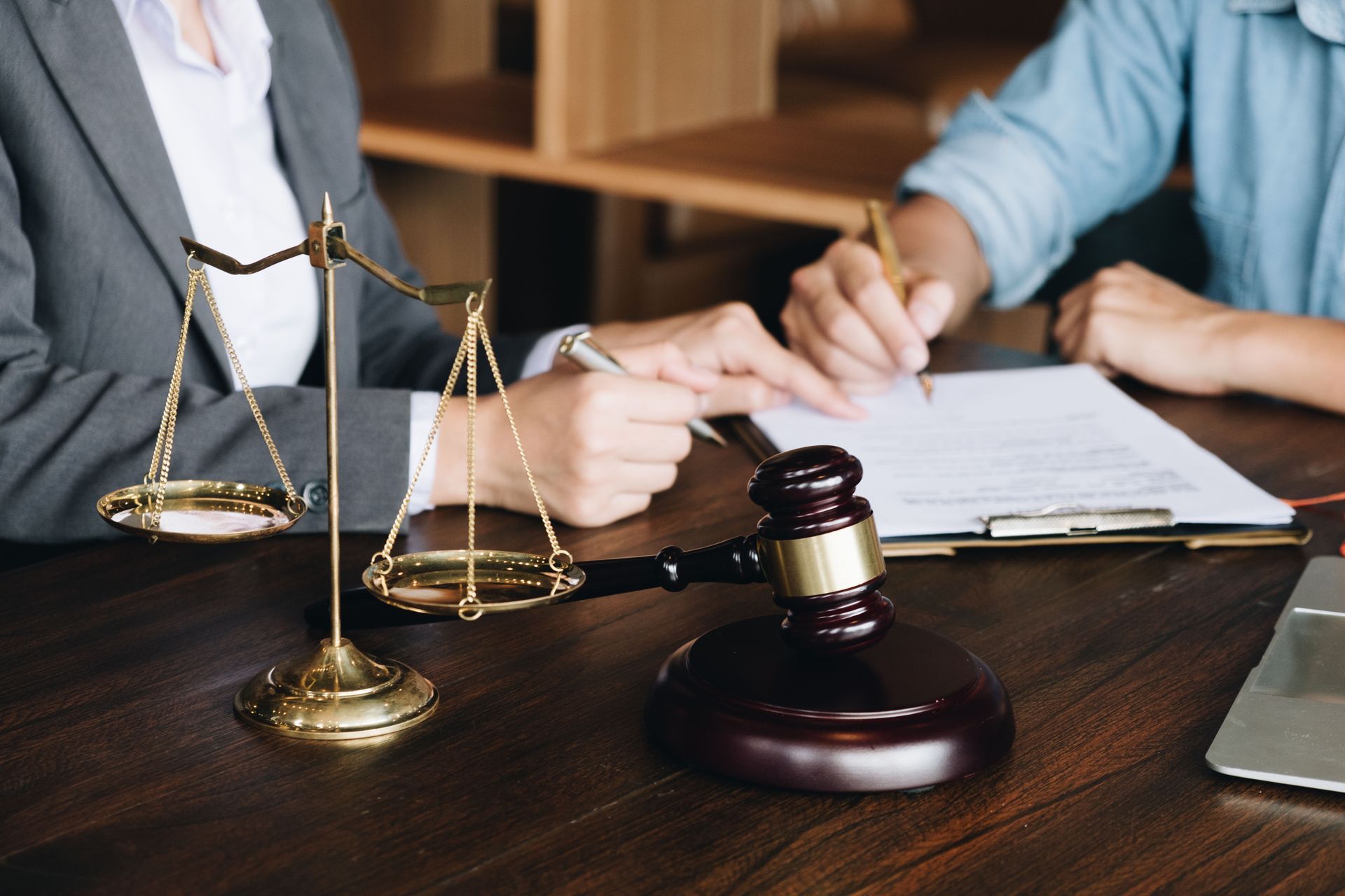 Lawyer’s desk with scales of justice, gavel, and people reviewing documents in a meeting