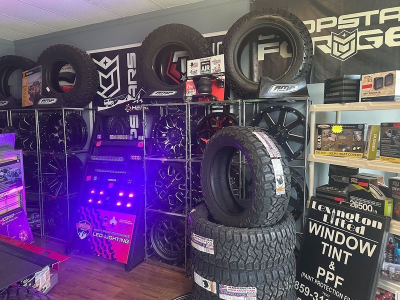 Tire shop display with stacked tires, wheel rims, and purple-lit equipment shelves