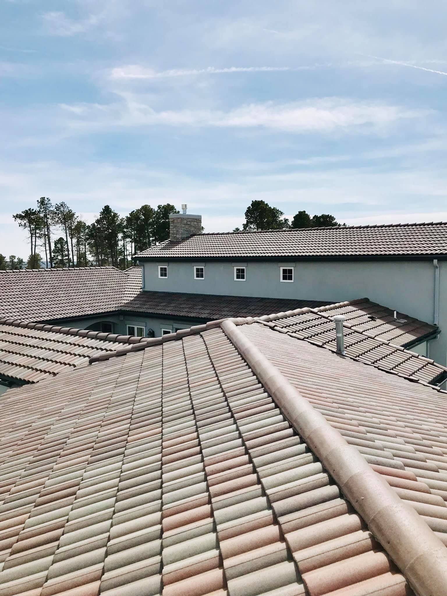Roofs with terracotta tiles on buildings under a partly cloudy sky.