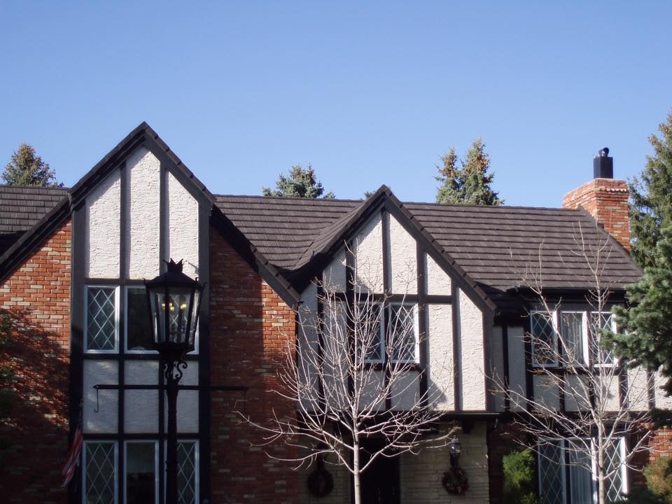 Tudor-style house with red brick, black trim, and a dark gray roof. A black lamppost in front.