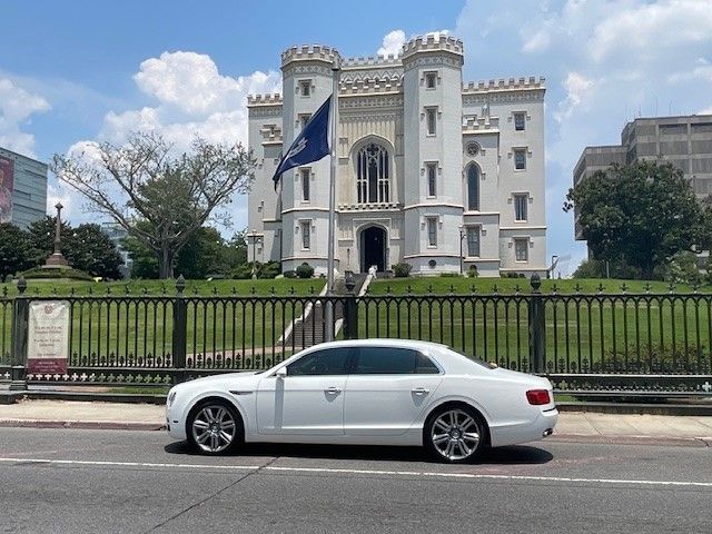 A white car is parked in front of a castle