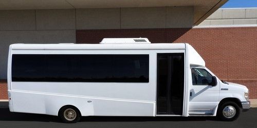 A white bus is parked in front of a brick building.