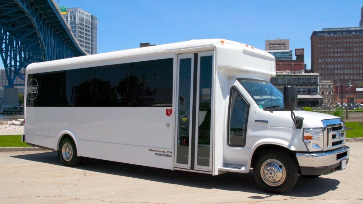 A white bus is parked in front of a bridge in a city.