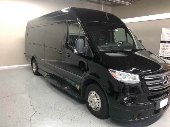 A black mercedes sprinter van is parked in a garage.