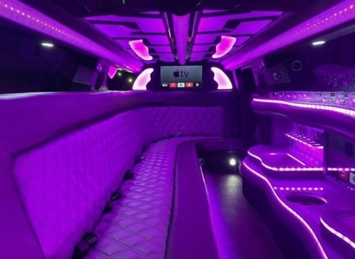 The inside of a purple limousine with a tv on the ceiling