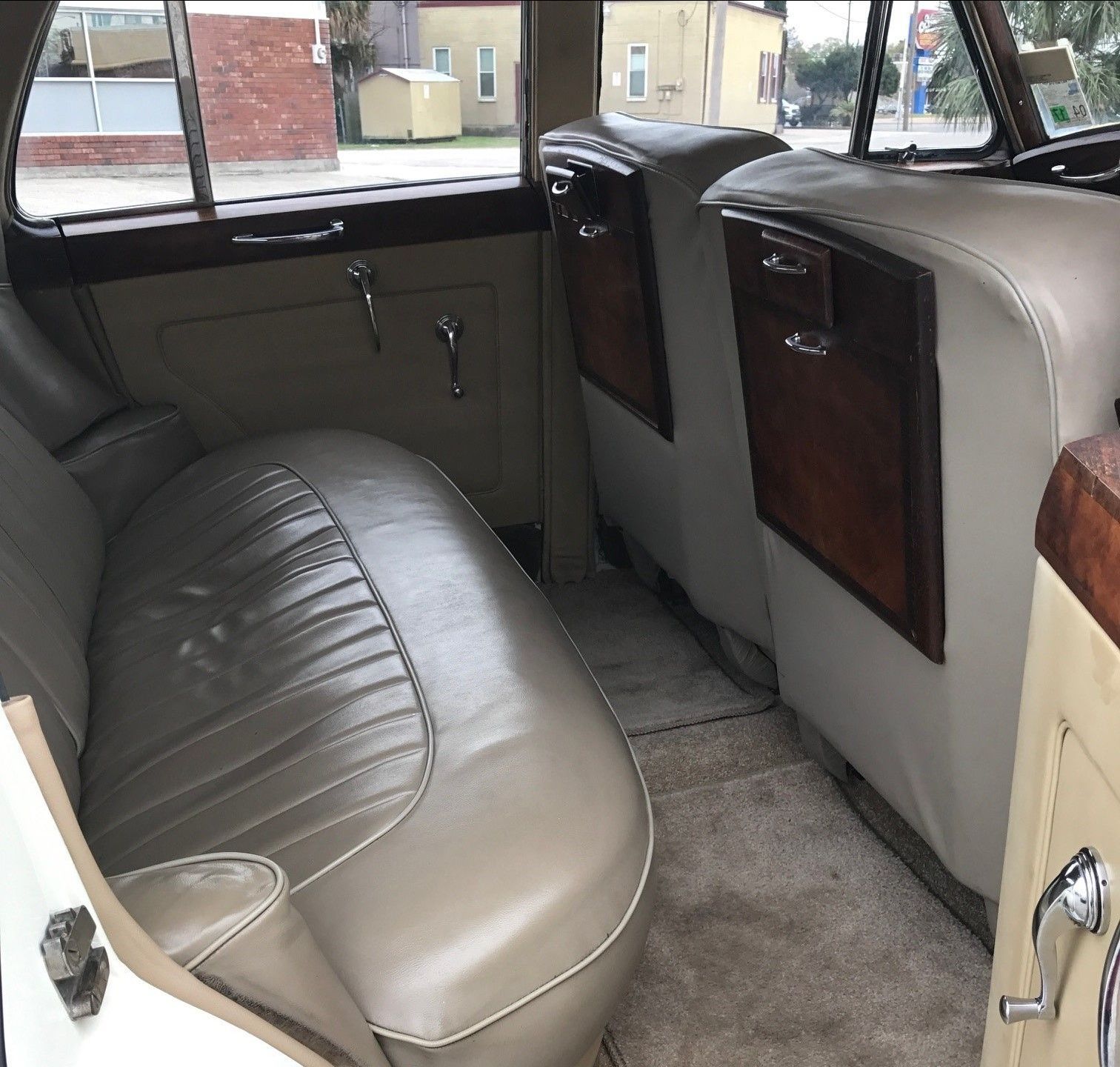 The back seat of a white car with tan leather seats.