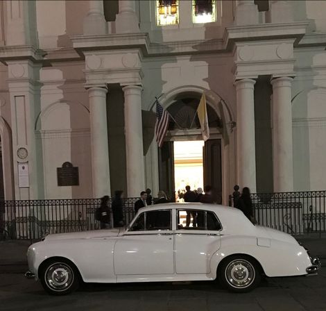 A white car is parked in front of a building at night.