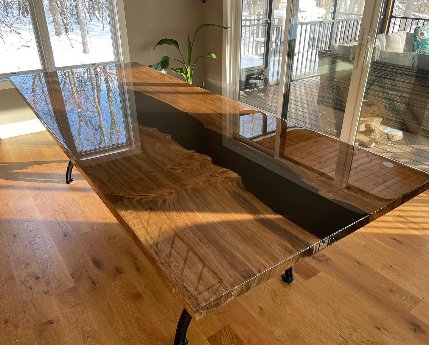 A wooden table with a glass top is sitting in a living room next to a window.