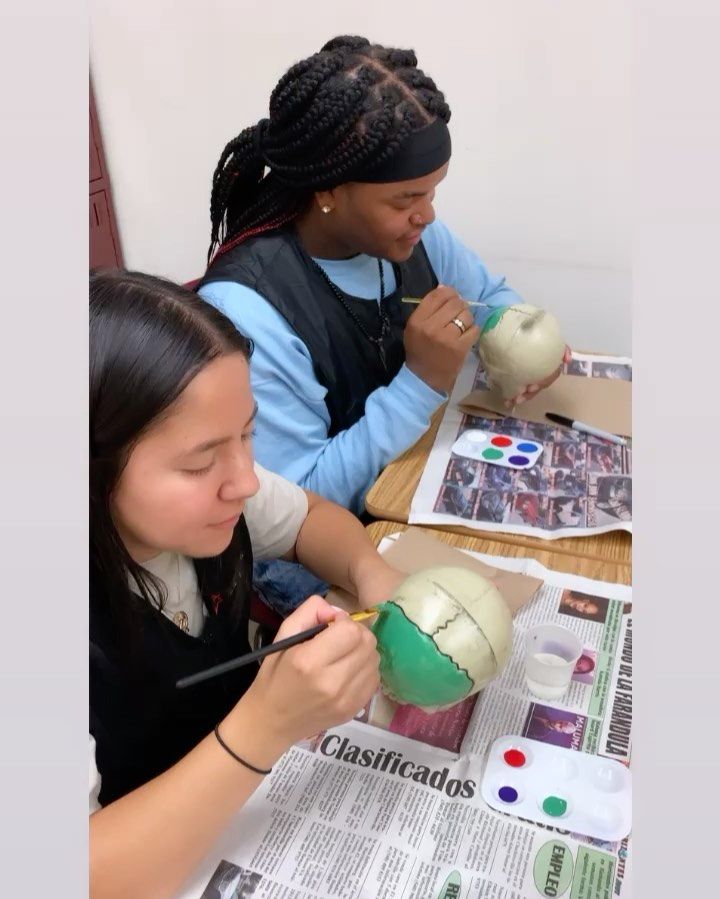 Two girls are sitting at a table with a newspaper that says clasificados